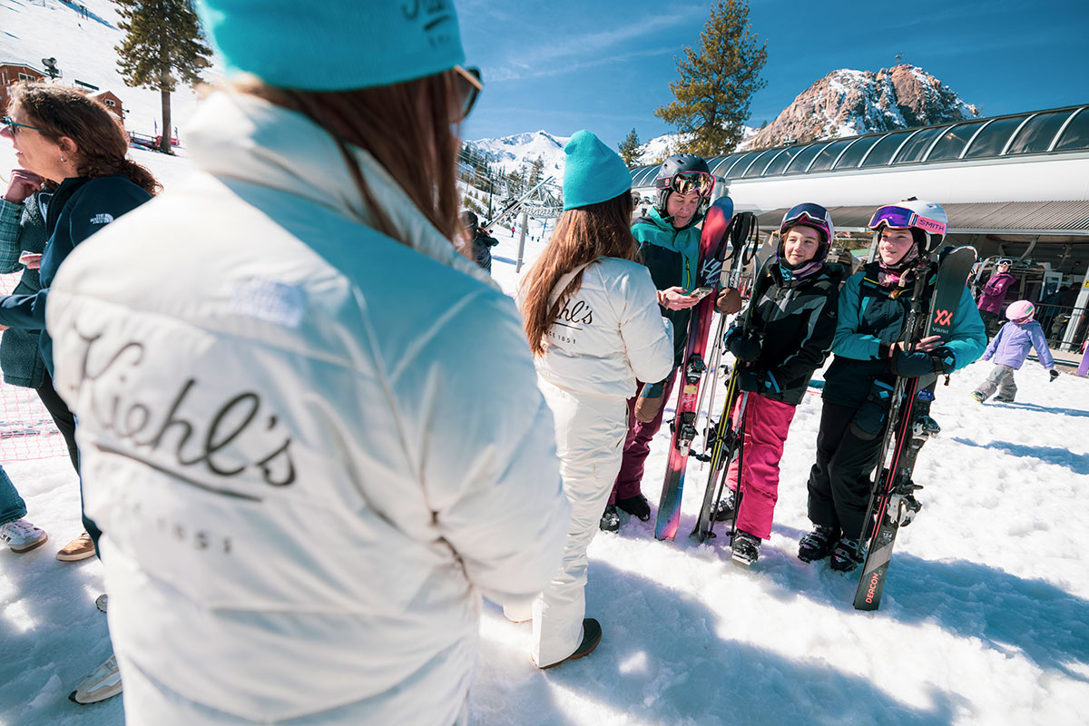 Kiehl's branded staff jackets at the base area with guests and skis
