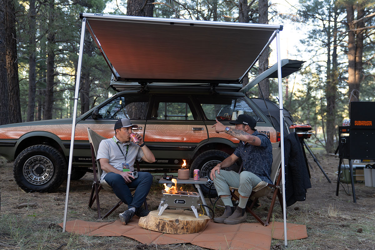 Guests relaxing fireside under a Subaru awning